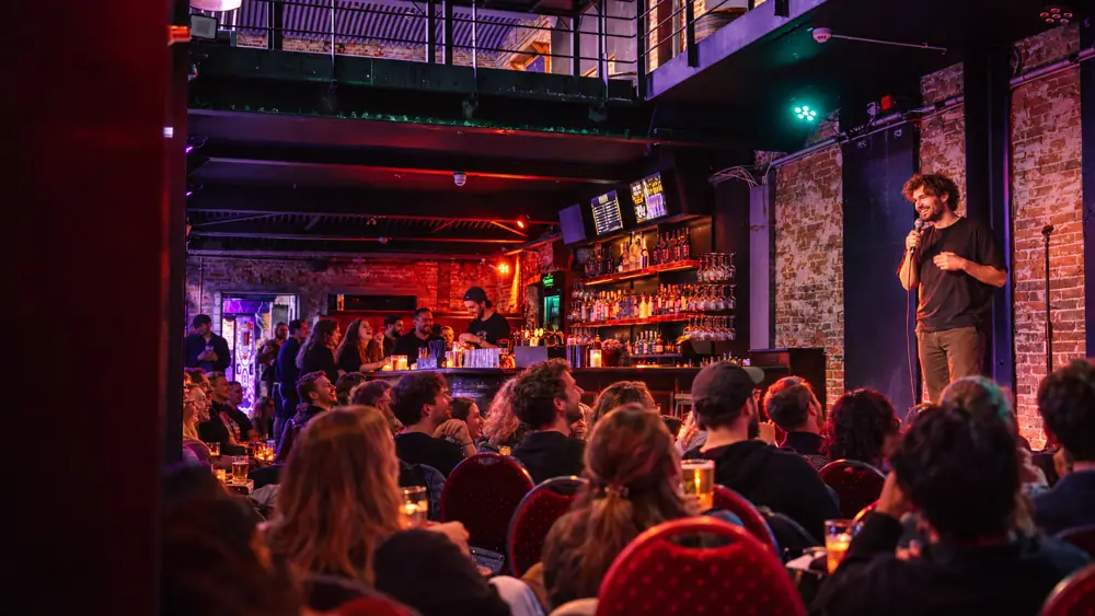 Comedian spielt direkt neben der Theke des Thomas Read, Gäste sitzen auf roten Stühlen