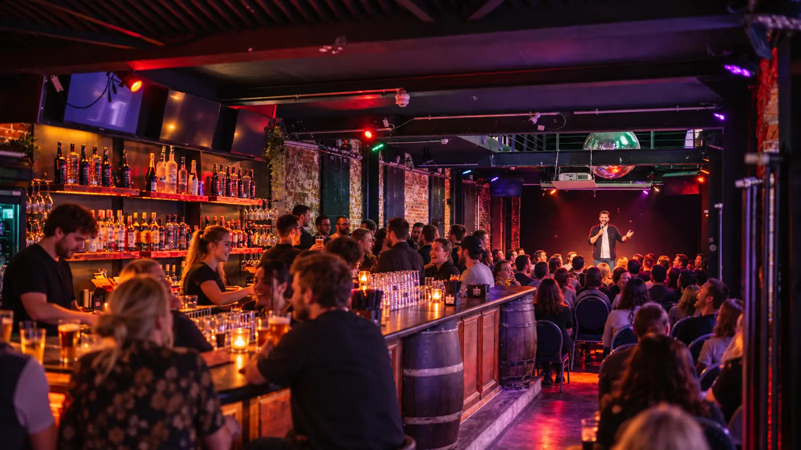 Pub Comedy im Thomas Read Hamburg: Theke mit Gästen links, hinten ein Comedian auf der Bühne vor vollen Stuhlreihen